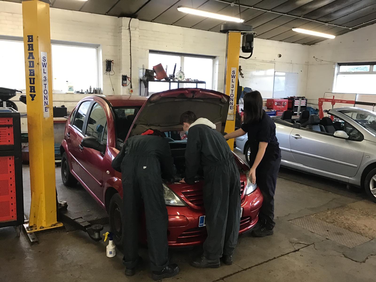 Group working under the bonnet of a car